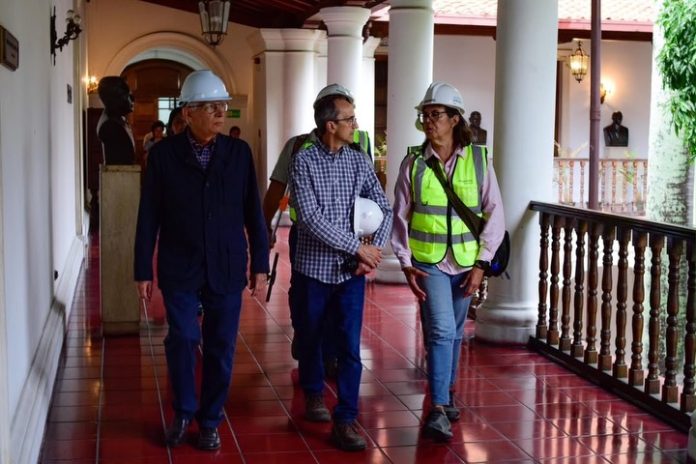 Autoridades con cascos de seguridad recorriendo un pasillo colonial en La Guaira
