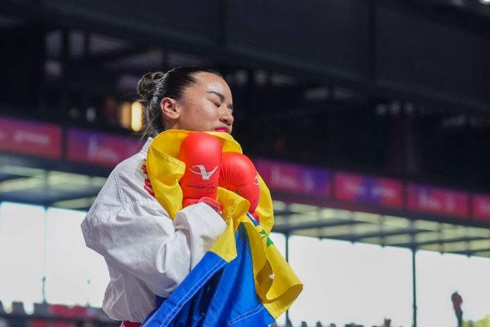 karateca venezolana Yorgelis Salazar con guantes rojos y la bandera de Venezuela