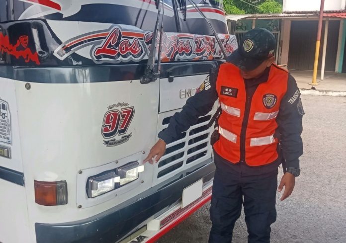 Funcionario de tránsito revisando las luces delanteras de un autobús en Miranda